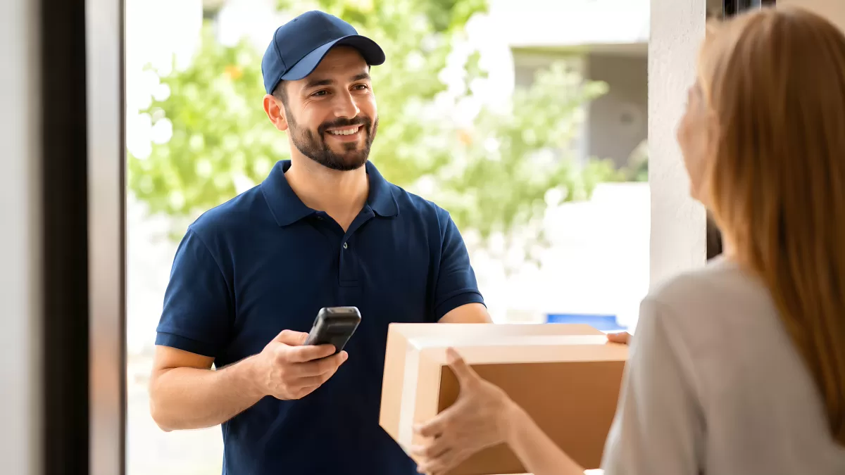 Paketbote übergibt Lieferung lächelnd an Kundin
