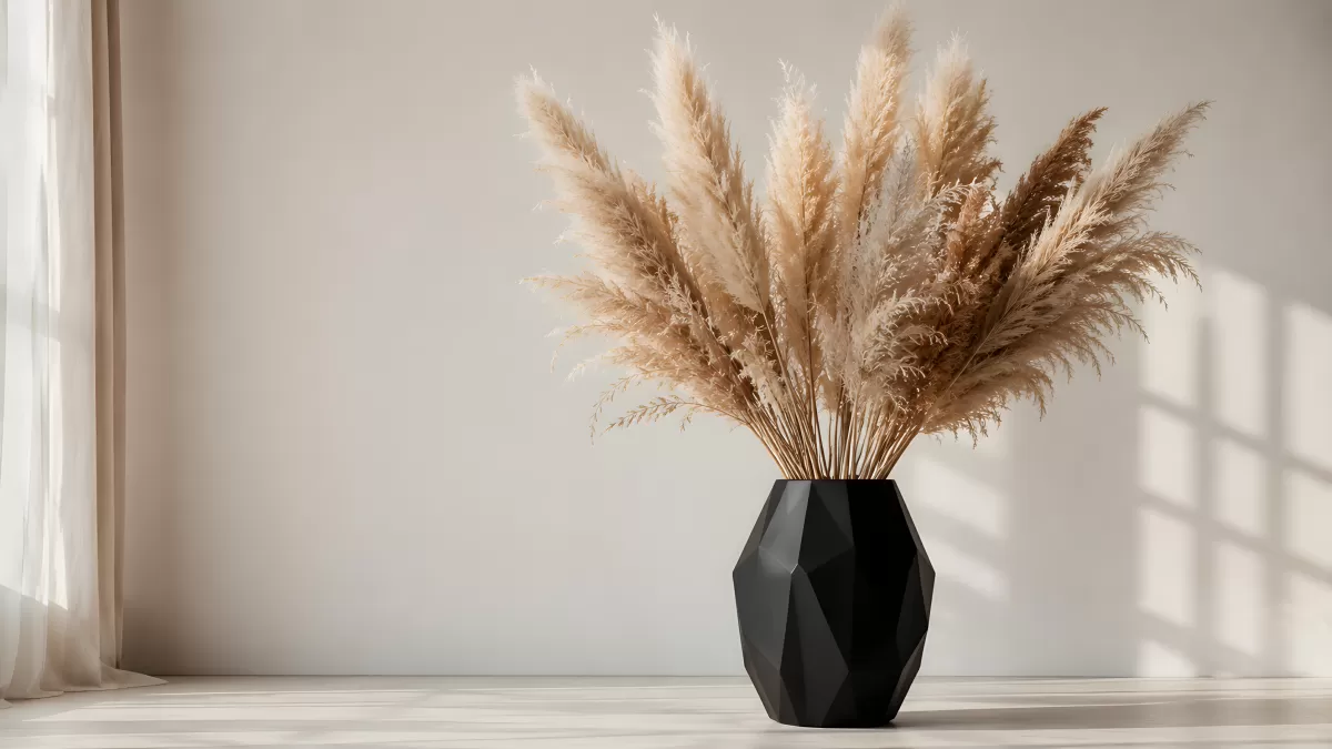 Pampasgras in schwarzer Vase vor heller Wand