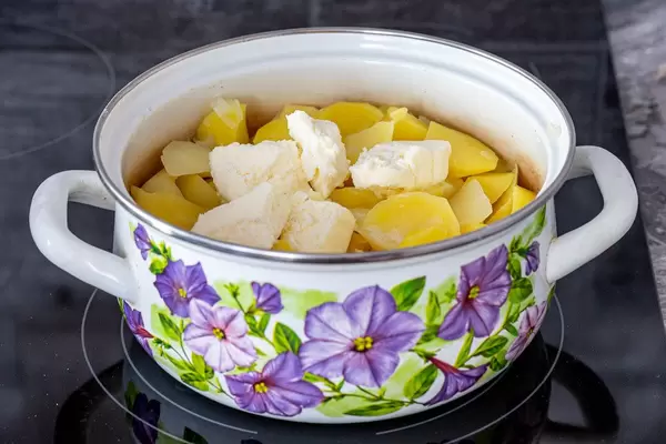 Pan with potatoes and pieces of butter on black kitchen cooking surface (Flip 2019)