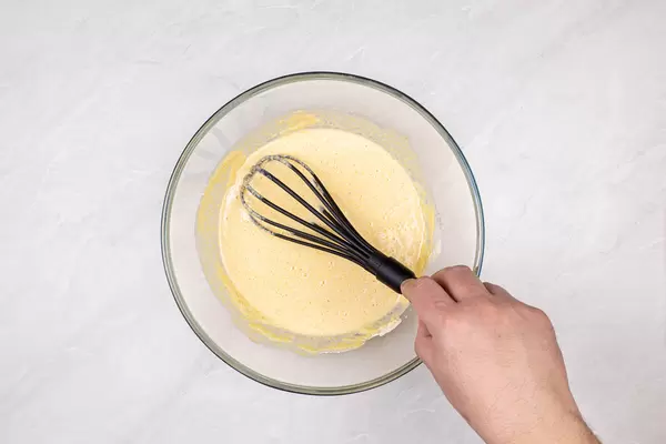 Pancake dough mixture in the bowl with hand above