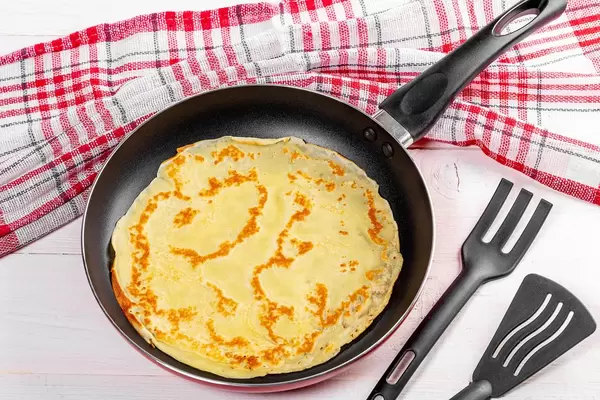 Pancake on a frying pan with a kitchen towel (Flip 2019)