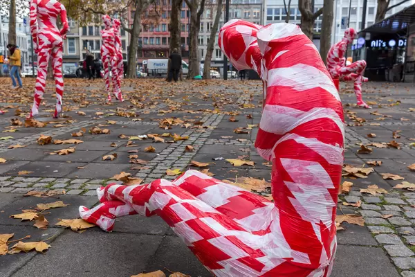 Pandemic art: close-up of a mannequin wrapped in red-white barrier tape at Neumarkt, Cologne