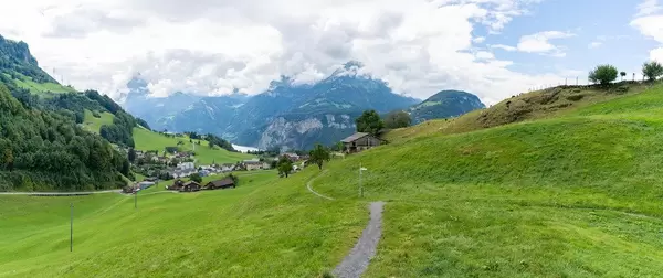 Panorama of Swiss green hills with path, village, mountains and lake Lucerne