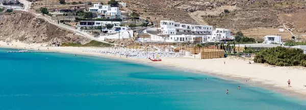 Panoramic image of the sandy beach of Kalo Livadi in Mykonos with the blue waters of the Aegean Sea