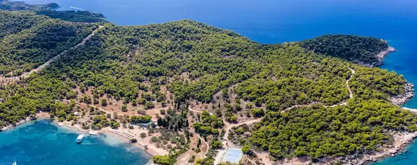Panoramic picture and aerial view of the Greek island Spetses with its green pine forest and the coast at the blue ocean