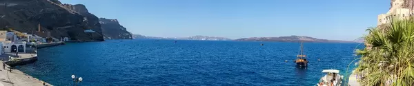 Panoramic shot in Santorini: cliffs, boats, the blue sea and very few people