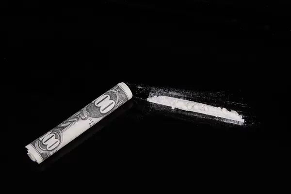 Paper currency and cocaine in line on table