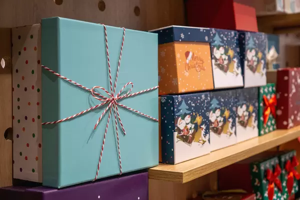 Paper Gift Boxes in different Sizes in Christmas Design on a Wooden Shelf in a Store