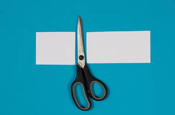 Paper with scissors on blue background