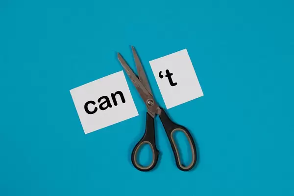 Paper with word Can't and scissors on blue background