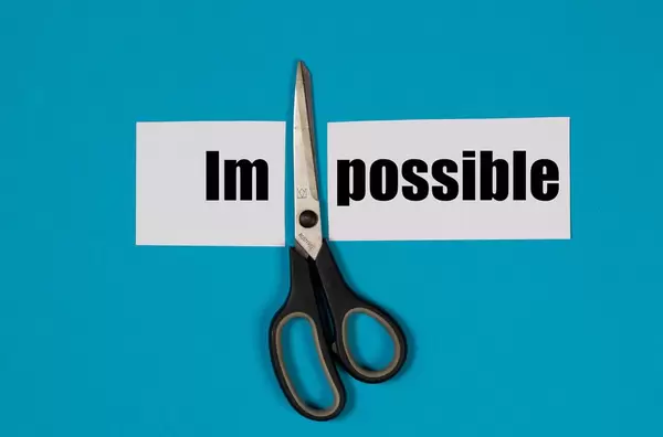 Paper with word Impossible and scissors on blue background