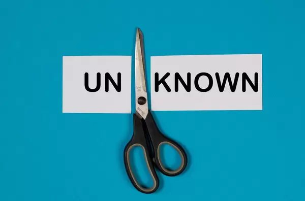 Paper with word Unknown and scissors on blue background