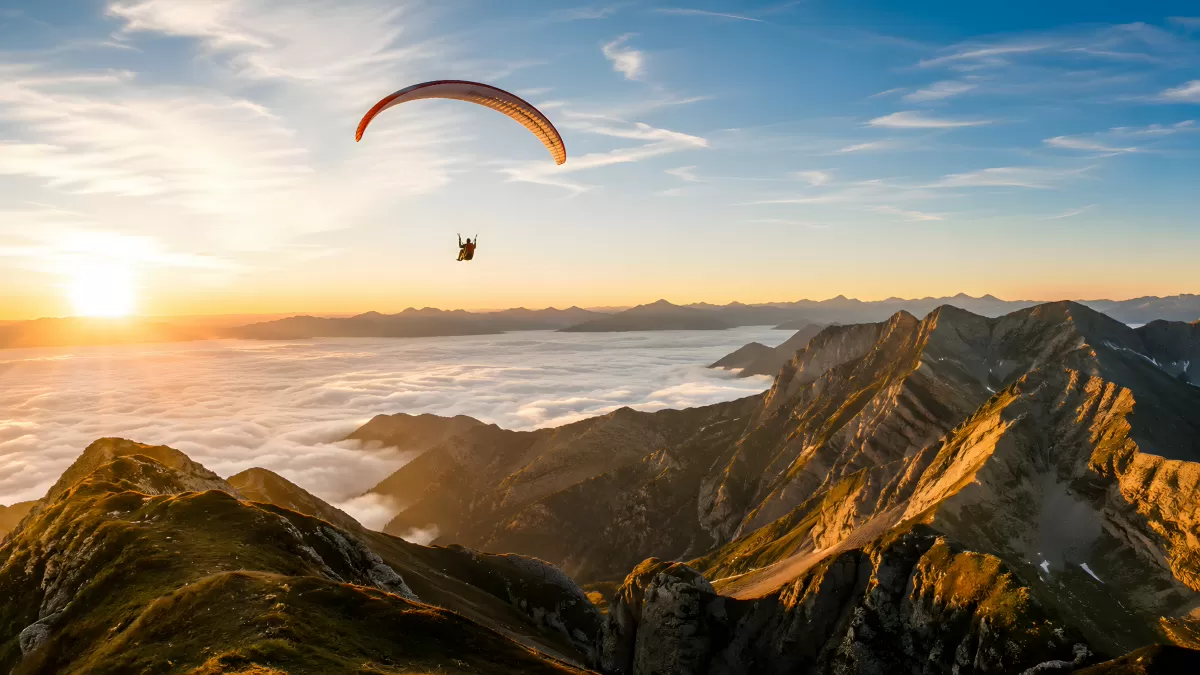 Paraglider über Alpengipfeln bei goldenem Sonnenuntergang