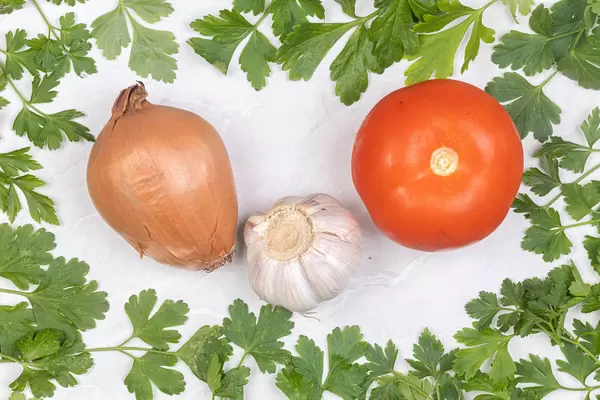 Parsley leaf frame with Onion Garlic and Tomato in the middle