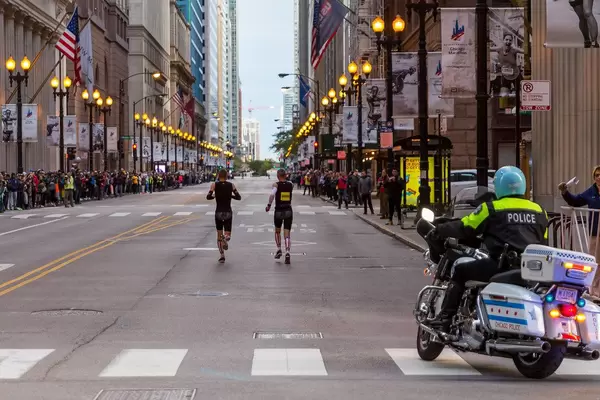 Participant running with support of a designated guide in matching black and stars and stripes outfit at the Chicago Marathon 2019