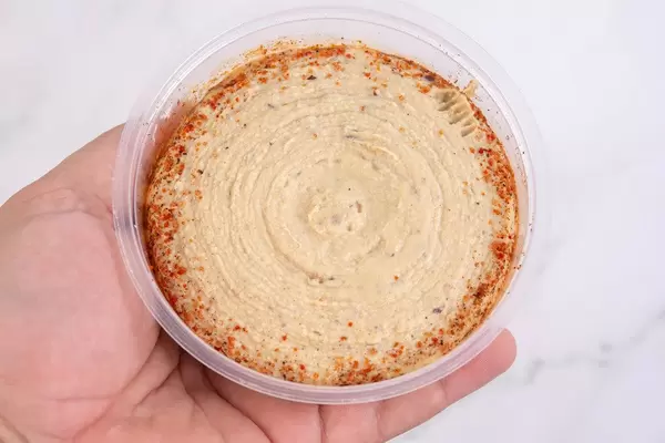 Partyfood: Hummus mit Oliven und Gewürzen in Einwegschüssel