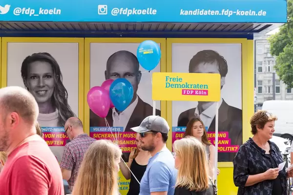 Passanten und ein Promotionstand der FDP im Hintergrund