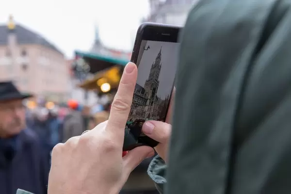Passantin macht mit Mobiltelefon Foto von Weihnachtsmarkt auf Domplatte mit Kölner Dom