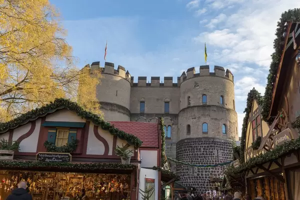 Passers-by stroll through the Christmas market in front of the old city wall of Cologne on Rudolfplatz in Cologne