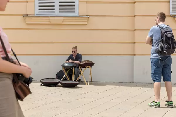 Passersby listening to a young man playing a hang