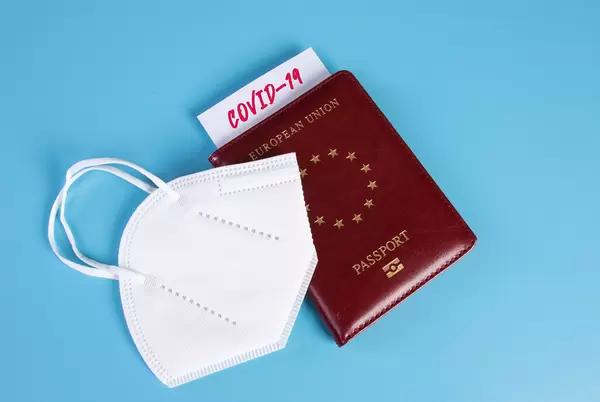 Passport and FFP2 face mask on blue background