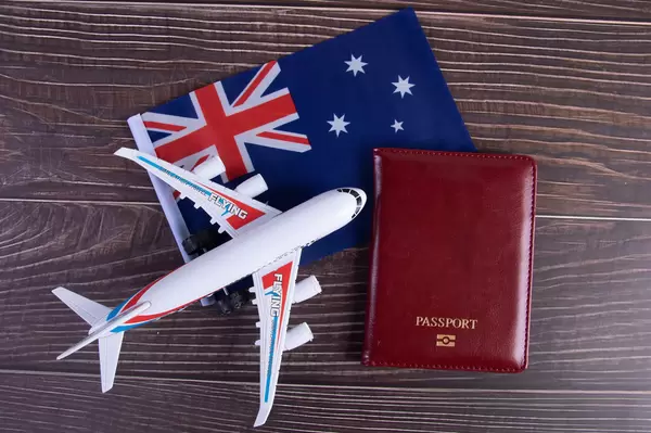 Passport, miniature airplane and flag of Australia on wooden table
