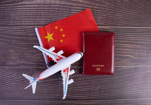 Passport, miniature airplane and flag of China on wooden table