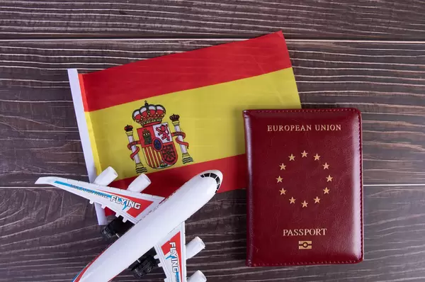 Passport, miniature airplane and flag of Spain on wooden table