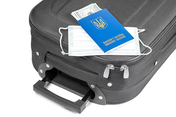 Passport with dollars, medical mask and suitcase