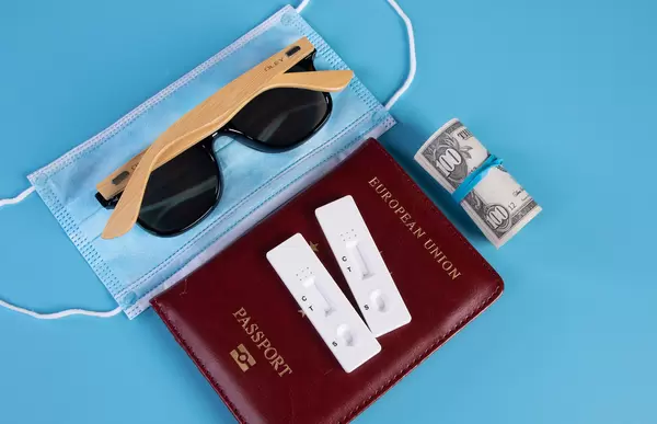 Passport with Rapid antigen test, face mask and sunglasses on blue background