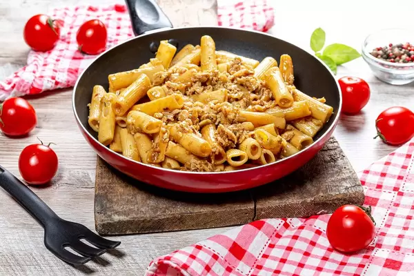 Pasta with minced chicken in a frying pan on a wooden background (Flip 2019)