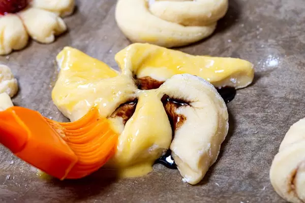 Pastry brush smears beaten egg on raw bun close up (Flip 2019)