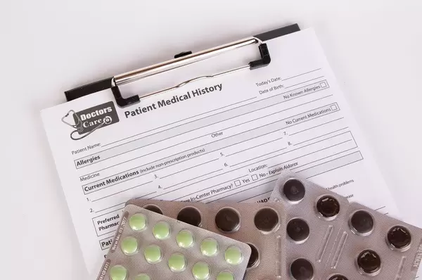 Patient Medical History form with pills on white table