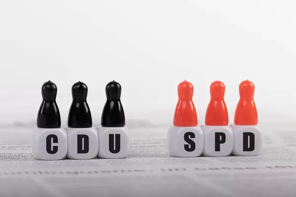 Pawn figurines with cubes and CDU and SPD text on newspaper