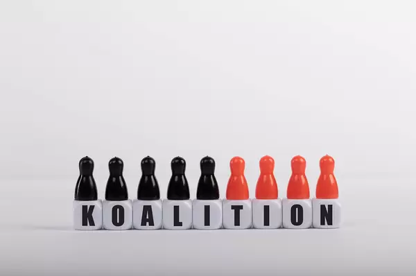 Pawn figurines with cubes and Koalition text on white background