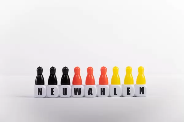 Pawn figurines with cubes and Neuwahlen text on white background