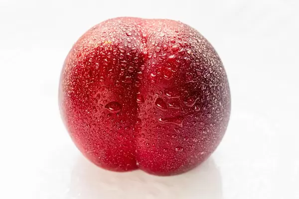 Peach nectarine with water drops on a white plate