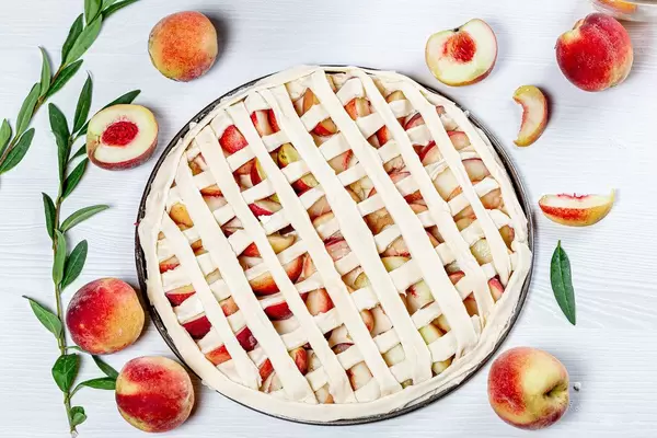 Peach pies and ingredients on white wooden background (Flip 2019)