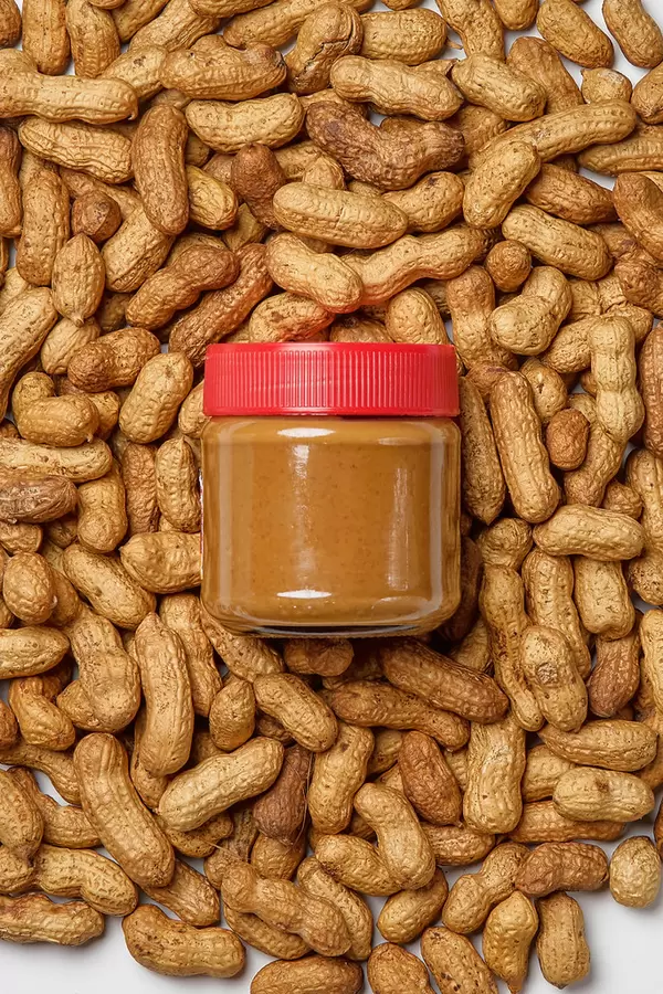 Peanut butter container with whole nuts background