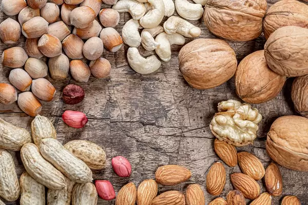 Peanuts, walnuts, almonds, cashews and hazelnuts on old wooden background