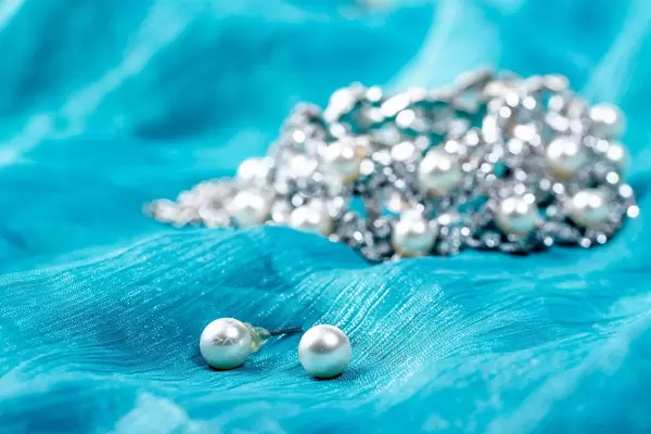Pearl earrings and necklace on green background
