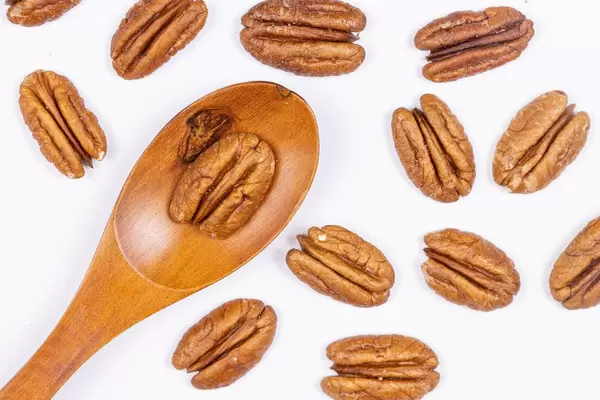 Peckans Nuts and wooden spoon on the white table