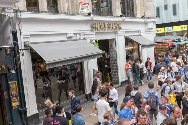 Pedestrians walking by a Shake Shack
