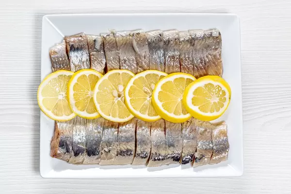 Peeled fillet of pickled herring with lemon slices