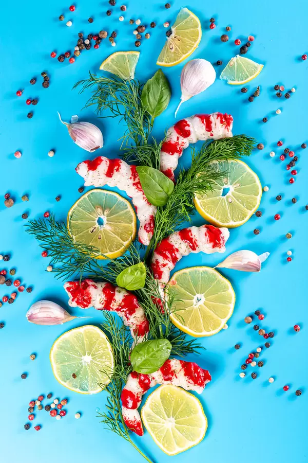 Peeled shrimps on a blue background with spices and herbs