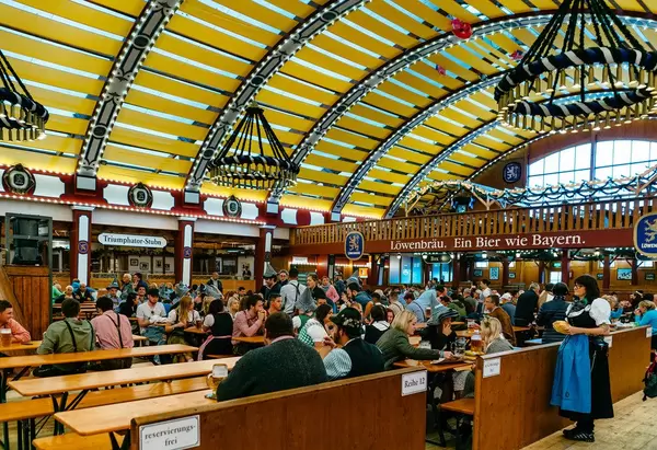 People having fun and drinking beer inside Löwenbräu tent at Oktoberfest