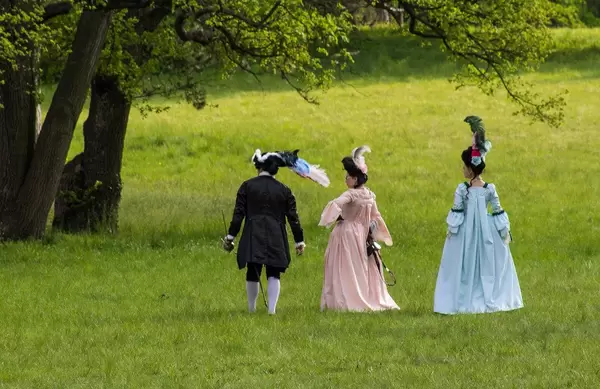 People in baroque costumes walking in park