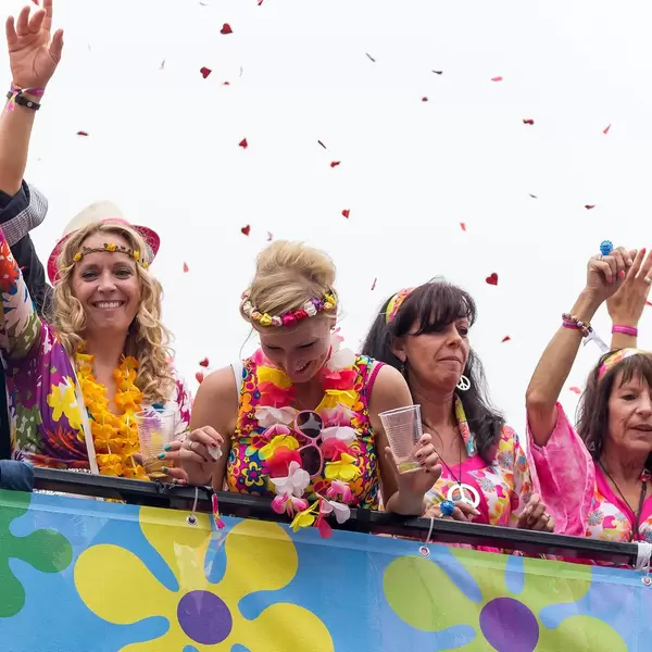 People in colorful outfits celebrating and drinking on a bus