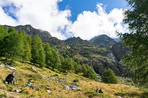 People resting on a long hike underneath epic looking Alpine cliffs
