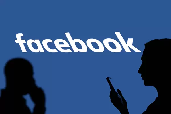 People silhouettes over Facebook online social media logotype